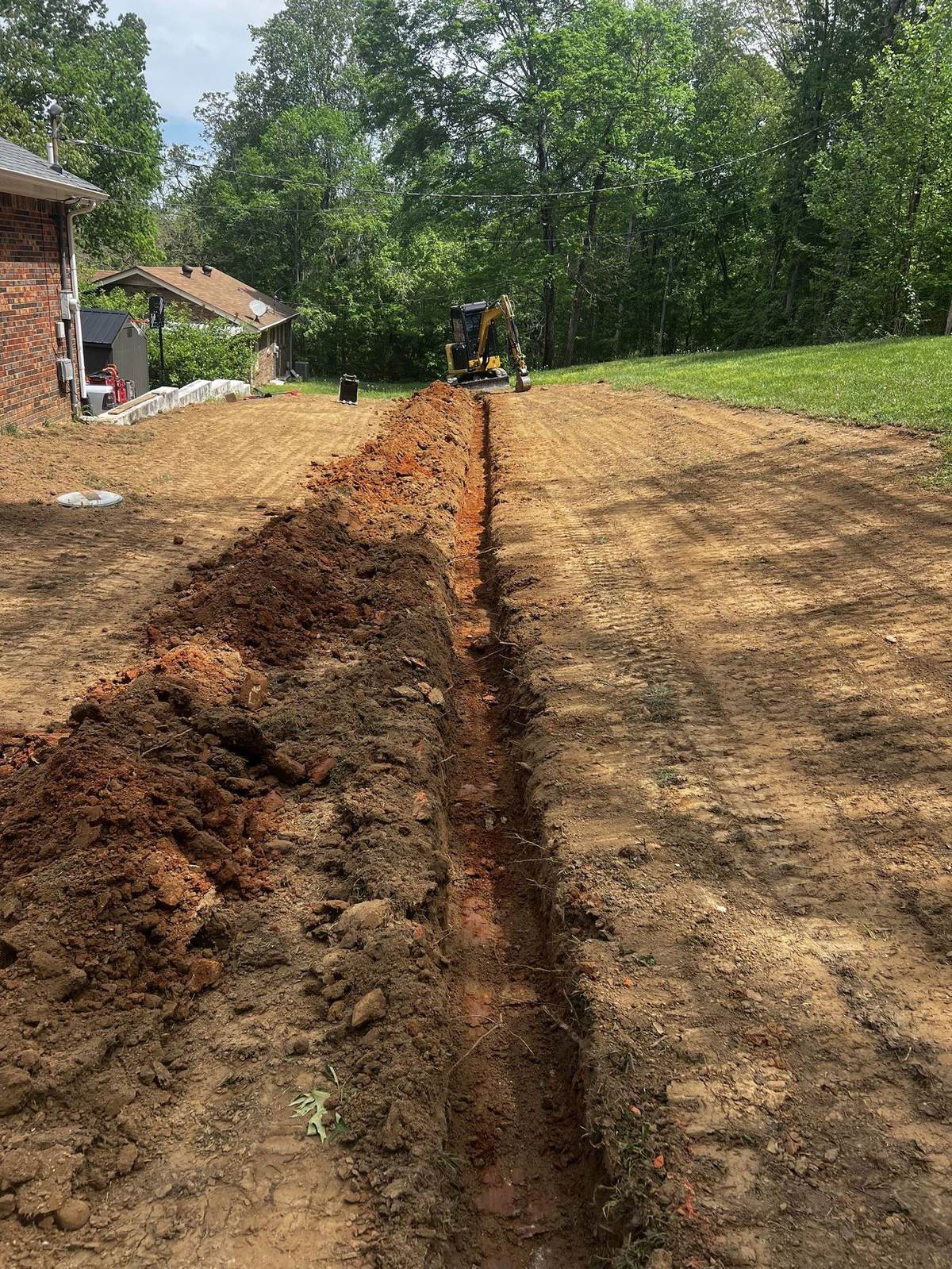 French drain trench dug and graded across a residential yard