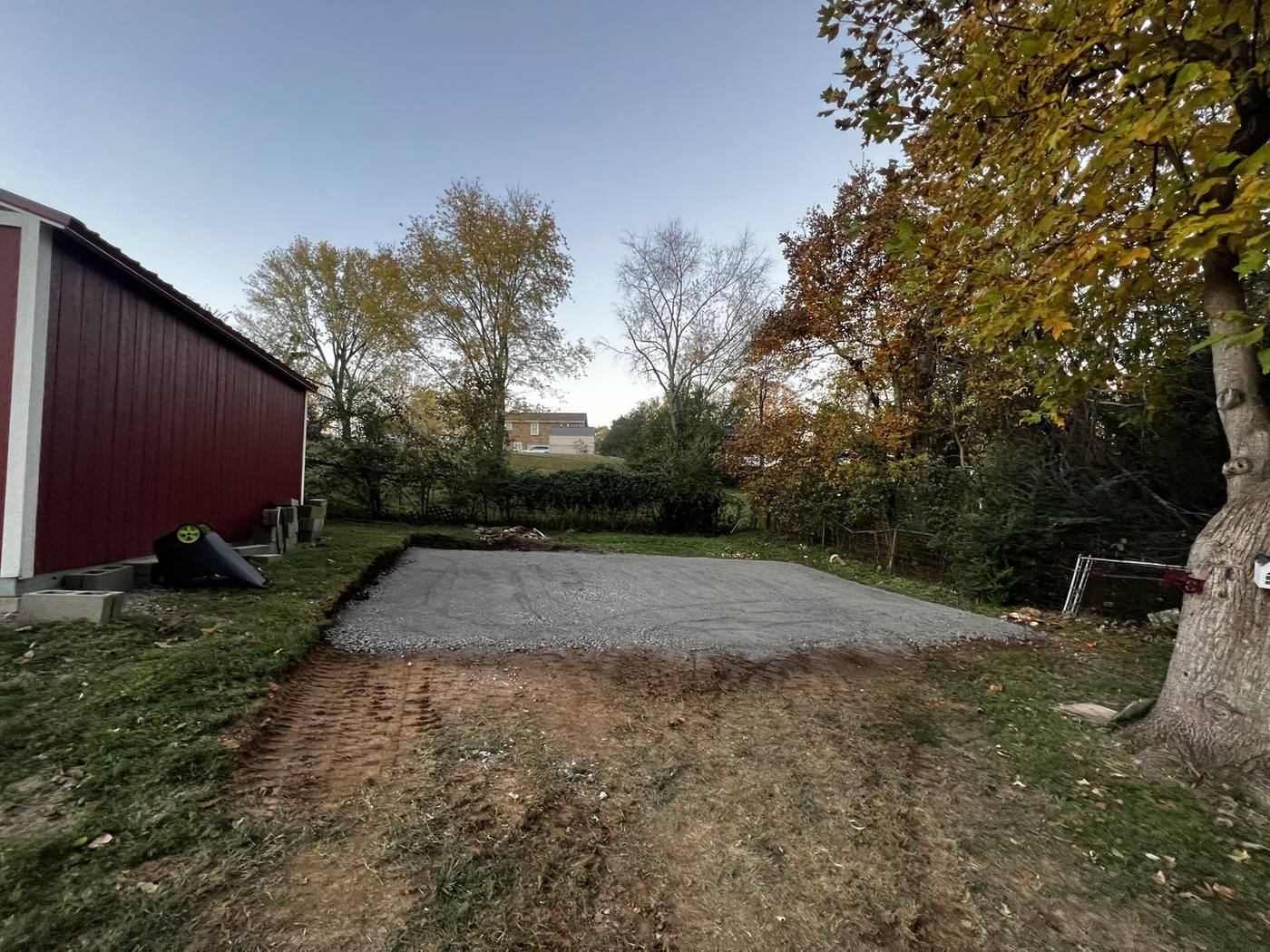 Fresh gravel parking pad installed beside a barn