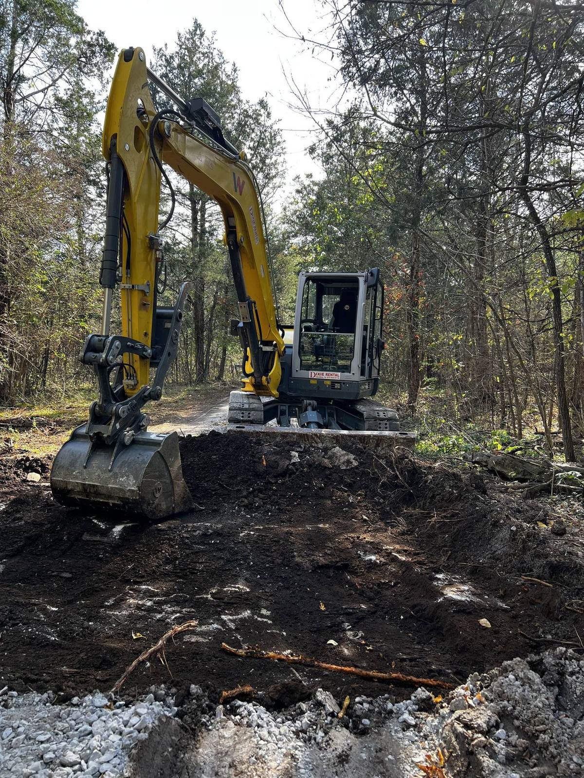Michael Way Acres excavator digging out a stump on a wooded lot